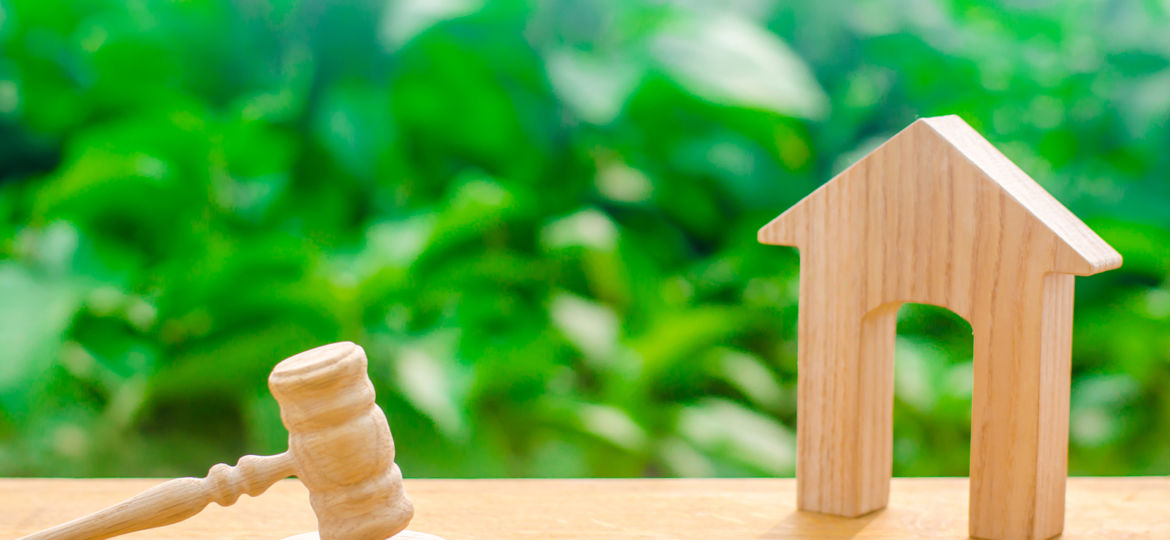 Wooden House And Hammer Of The Judge On A Green Background. Conc